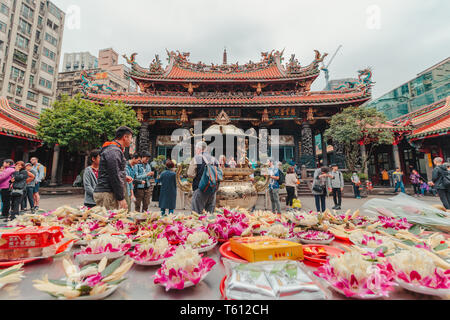 Foods and Flowers placed by visitors at Longshan Temple, one of the most popular tourist destination, to pay respect and worship the holy spirit Stock Photo