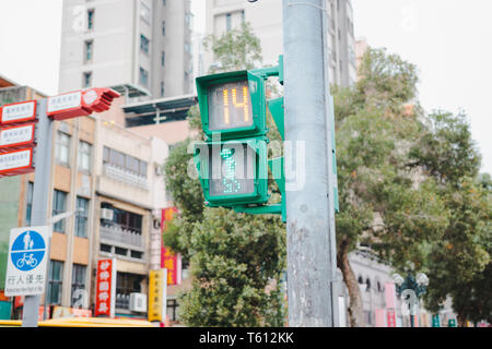 Pedestrian Traffic light in Taiwan showing green light and timer with old building and local business in the background Stock Photo