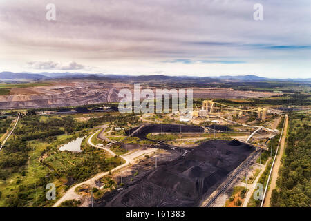 Huge open cut black coal mine in Hunter Valley rural region of Australia excavating fossil fuel for electrisity power station in elevated aerial view  Stock Photo