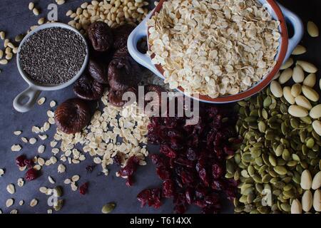 Raw oats with dried fruit, nuts and seeds on a grey slate background Stock Photo