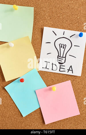 painted light bulb with word idea and colored blank notes on cork board Stock Photo