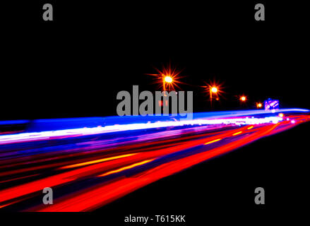 Cars light trails on a curved highway at night. Night traffic trails. Motion blur. Night city road with traffic headlight motion. Cityscape. Light up 