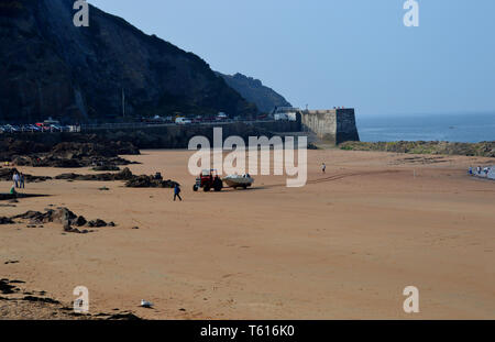 A Tractor Pulling a Boat up the Beach to the Slipway on Greve De Lecq Beach on the Island of Jersey, Channel Isles, UK. Stock Photo