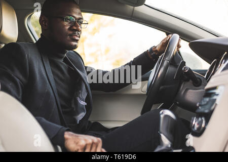 The man presses the buttons in the car. Adjustment of audio volume control. Stock Photo