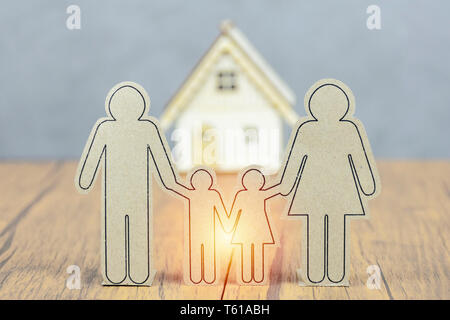 Home buying concept planning. Family ties are like protected islands. Mass symbol, father, mother, child, holding hands. Background is a model house. Stock Photo