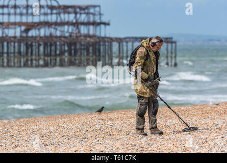 Man searching for treasure on a beach using a metal detector in Brighton, East Sussex, England, UK. Stock Photo