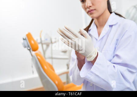 Dentist putting on latex gloves Stock Photo