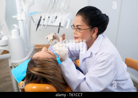 Mature Vietnamese dentist working with young patient Stock Photo