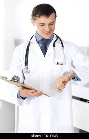 Doctor man using clipboard for filling up medication history records. Perfect medical service in clinic. Physician at work in hospital. Medicine and Stock Photo