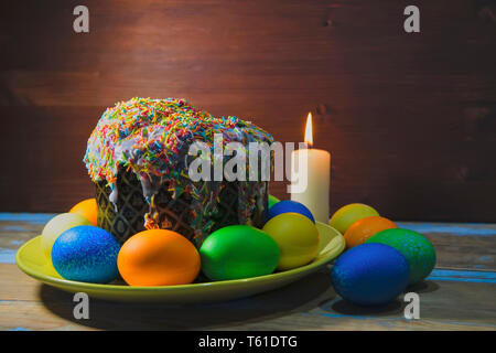 Beautiful Easter composition with Easter cake, lighted candle and painted eggs on wooden table. Copy space. Stock Photo