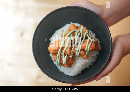 Chicken fried, Japanese style called Kara-age, on the rice in the black bowl on the wooden table. Stock Photo