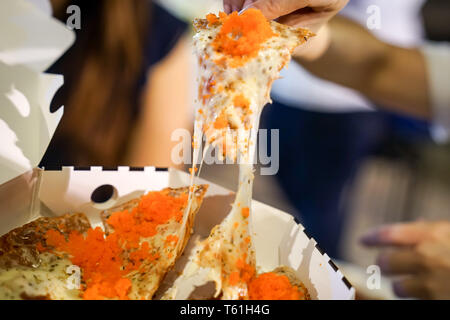 Woman's hand take pizza pices out from pizza plate in foodtruck event, Cheese's pizza is stretced by her. Stock Photo
