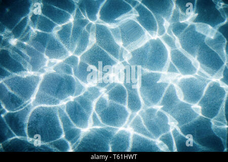 Abstract movement of light touching wave on blue water surface reflecting on ground of swimming pool. Stock Photo