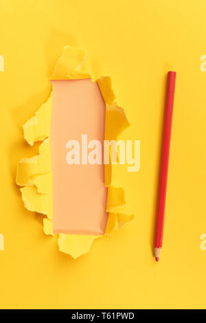 Yellow torned paper over orange background with pencil Stock Photo