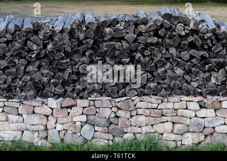 Stacked and cut wood on the old stone garden Stock Photo