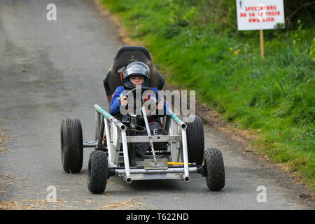 Soapbox derby in Wray, Lancashire, UK. 28th April, 2019. Wacky Wrayces; Callum Hannafin at the Scarecrow Festival competing in the junior soap box derby races. The 2019 theme, chosen by the local school, is to highlight the themes of “Evolution: Extinct, Endangered, Existing” This fun festive community event the annual Wray Scarecrow Festival in Lancashire is now in its 26th year and draws thousands of visitors to the rural village for the April celebration. Credit: MediaWorldImages/AlamyLiveNews. Stock Photo
