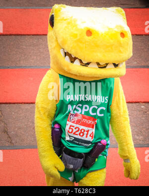 London, UK. 28th Apil 2019. The NSPCC 'Pantosaurus' crosses the finish line. Over 40,000 starters are once again competing in the Virgin London Marathon, including those who take on the race for charities, in running clubs, in memory of loved ones and as personal lifetime goals. Credit: Imageplotter/Alamy Live News Stock Photo