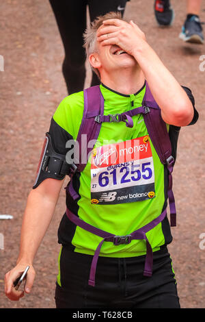 London, UK. 28th Apil 2019. An exhausted runner on the finish line. Over 40,000 starters are once again competing in the Virgin London Marathon, including those who take on the race for charities, in running clubs, in memory of loved ones and as personal lifetime goals. Credit: Imageplotter/Alamy Live News Stock Photo