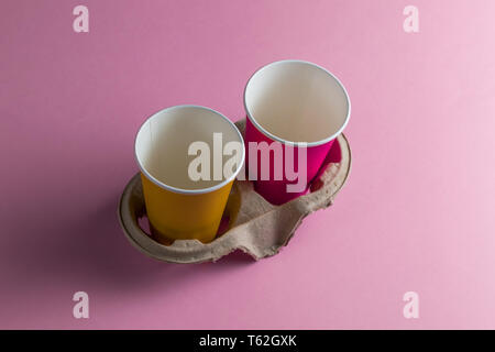 two violet and yellow empty paper cups isolated on pink background. close up photo.recycling paper Stock Photo