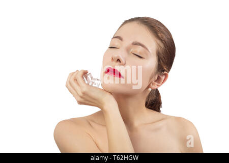 serious young woman applying ice cubes on her face skin, isolated on white background, closed eyes Stock Photo