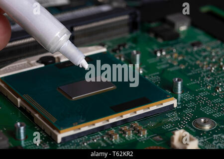 A tube of thermal grease over the processor chip. Computer assembly stage. Part of laptop Stock Photo