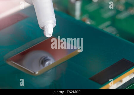 A tube of thermal grease over the processor chip. Computer assembly stage. Part of laptop Stock Photo