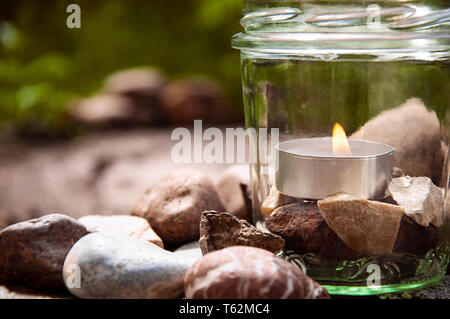 Burning tea light candle glass stones cropped right grasses background  by jziprian Stock Photo
