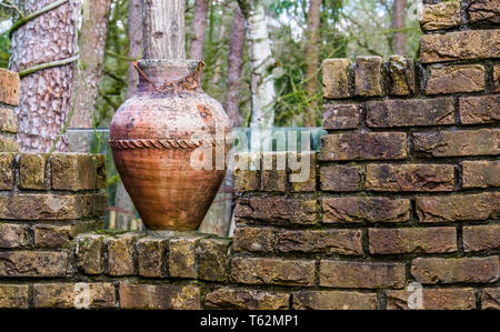 old chipped roman vase on a brick wall, outdoor garden decorations and architecture Stock Photo