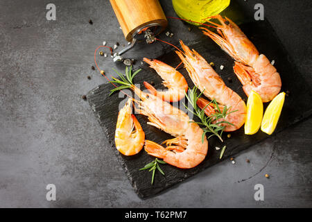 Seafood. Raw shrimps with spice and lemon on a slate board. Free space for your text. Stock Photo