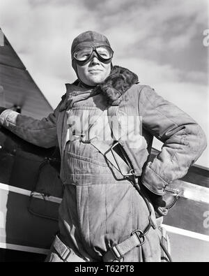 1940s DETERMINED EXPERIENCED MAN AVIATOR WEARING LEATHER FLYING HELMET GOGGLES CANVAS FLIGHT SUIT STANDING READY BY BIPLANE - a1372 HAR001 HARS LIFESTYLE PLANES SATISFACTION HISTORY CONFLICT READY WW2 JOBS RURAL COPY SPACE HALF-LENGTH PERSONS INSPIRATION GOGGLES MALES RISK CONFIDENCE TRANSPORTATION EXPRESSIONS B&W FREEDOM SKILL OCCUPATION HAPPINESS SKILLS ADVENTURE AIRPLANES CANVAS STRENGTH COURAGE EXPERIENCED EXCITEMENT LOW ANGLE RECREATION WORLD WARS PRIDE WORLD WAR WORLD WAR TWO WORLD WAR II BY AUTHORITY AVIATION OCCUPATIONS UNIFORMS CONCEPTUAL AVIATOR STYLISH WORLD WAR 2 DETERMINED Stock Photo
