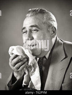 1940S SUFFERING senior man about to sneeze into handkerchief - a3889 HAR001 HARS STUDIO SHOT HEALTHINESS ILLNESS MANAGER PERSONS MALES AILMENT ABOUT EXECUTIVES EXPRESSIONS MIDDLE-AGED B&W MIDDLE-AGED MAN HEALTHCARE SUIT AND TIE SUFFERING WELLNESS OLDSTERS PREVENTION HEAD AND SHOULDERS FEVER OLDSTER ALLERGY DISTRESSED HANDKERCHIEF HEALING DIAGNOSIS DISTRESS LOW ANGLE EXPLOSIVE HEALTH CARE INTO TO IMPAIRMENT TREATMENT WIDE LAPEL ELDERS BOSSES IRRITATION CONCEPTUAL COMPULSIVE VIRUS ALLERGIC MANAGERS SPREADING BLACK AND WHITE CAUCASIAN ETHNICITY DISEASE HAR001 OLD FASHIONED Stock Photo