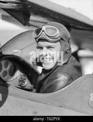 1930s MAN PILOT SITTING IN OPEN AIR COCKPIT SMILING LOOKING OVER HIS SHOULDER  - a4425 HAR001 HARS WELCOME PLEASED JOY LIFESTYLE PLANES JOBS PERSONS GOGGLES MALES TRANSPORTATION EXPRESSIONS B&W EYE CONTACT SKILL OCCUPATION HAPPINESS SKILLS HEAD AND SHOULDERS CHEERFUL ADVENTURE AIRPLANES HIS EXCITEMENT AUTHORITY AVIATION OCCUPATIONS SMILES COCKPIT AVIATOR JOYFUL MID-ADULT MID-ADULT MAN BIPLANE BLACK AND WHITE BRAVE CAUCASIAN ETHNICITY HAR001 OLD FASHIONED Stock Photo