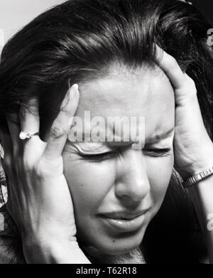 1970s BRUNETTE WOMAN HANDS TO TEMPLES PAINFUL FACIAL EXPRESSION STRESS PAIN HEADACHE MIGRAINE - a8039 HAR001 HARS LADIES PERSONS NERVOUS AFRAID AILMENT HEADACHE EXPRESSIONS B&W SADNESS BRUNETTE ANXIETY SUFFERING HEAD AND SHOULDERS ANXIOUS POWERFUL DESPAIR FEELING MOOD MENTAL HEALTH CONCEPTUAL GLUM THREATENED FEARFUL UNEASY WINCE NIGHTMARE POOR HEALTH TENSION AILING EMOTION EMOTIONAL EMOTIONS MISERABLE PAINFUL TOO LOUD WINCING YOUNG ADULT WOMAN BLACK AND WHITE CAUCASIAN ETHNICITY EYES CLOSED HAR001 HISPANIC ETHNICITY MENTAL ILLNESS MIGRAINE OLD FASHIONED Stock Photo