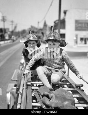 1930s TWO SMILING EXCITED PRETEEN BOYS WEARING FIREMAN SAFETY HELMETS CLIMBING SITTING RIDING PLAYING ON BACK OF A FIRE TRUCK - b11918 HAR001 HARS BALANCE SAFETY TEAMWORK PLEASED JOY LIFESTYLE SPEED CELEBRATION COPY SPACE FRIENDSHIP FULL-LENGTH INSPIRATION MALES RISK CONFIDENCE EXPRESSIONS B&W EYE CONTACT FIREMAN DREAMS HAPPINESS CHEERFUL ADVENTURE STRENGTH COURAGE CHOICE EXCITEMENT POWERFUL RECREATION SPECIAL OF ON OPPORTUNITY OCCUPATIONS PRETEEN SMILES CONCEPTUAL ESCAPE IMAGINATION JOYFUL STYLISH UNUSUAL HELMETS EXCITING EXPERIENCE JUVENILES PRE-TEEN PRE-TEEN BOY TOGETHERNESS BLACK AND WHITE Stock Photo
