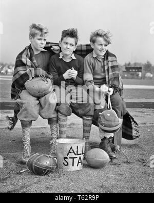 1940s THREE BOYS SITTING ON BENCH WRAPPED IN BLANKET HOLDING  FOOTBALL HELMETS WATCHING GAME FACIAL EXPRESSIONS AND GESTURES - b13536 HAR001 HARS BENCH STRESS NOSTALGIC GAMES PAIR SUBURBAN URBAN DEPRESSION EXPRESSION OLD TIME NOSTALGIA BROTHER OLD FASHION 1 JUVENILE FACIAL BLANKET TEAMWORK COMPETITION ATHLETE PLEASED JOY LIFESTYLE CELEBRATION WINNING BROTHERS MOODY HEALTHINESS COPY SPACE FULL-LENGTH PHYSICAL FITNESS INSPIRATION MALES TEENAGE BOY ATHLETIC SNEAKERS SIBLINGS EXPRESSIONS TROUBLED PLAYERS B&W SADNESS EYE CONTACT DREAMS HAPPINESS CHEERFUL ANXIOUS STRENGTH COURAGE AND EXCITEMENT Stock Photo