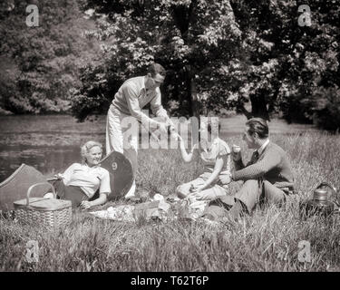 1930s TWO COUPLES MEN AND WOMEN ON CANOE TRIP SITTING ON GRASSY BANK ENJOYING A PICNIC LUNCH TOGETHER - c216 HAR001 HARS CANOE JOY LIFESTYLE CELEBRATION FEMALES MARRIED RURAL SPOUSE HUSBANDS COPY SPACE FRIENDSHIP FULL-LENGTH LADIES PHYSICAL FITNESS PERSONS INSPIRATION CARING MALES SERENITY TRANSPORTATION B&W PARTNER SUMMERTIME FREEDOM WIDE ANGLE ACTIVITY SUNSHINE HAPPINESS PHYSICAL CANOES ADVENTURE STRENGTH TRIP AND ENJOYING RECREATION ON CONNECTION CONCEPTUAL ESCAPE FLEXIBILITY GRASSY MUSCLES STYLISH SUNLIT INFORMAL RELAXATION SPRINGTIME TOGETHERNESS WIVES YOUNG ADULT MAN YOUNG ADULT WOMAN Stock Photo