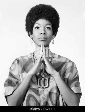1960s AFRICAN AMERICAN WOMAN AFRO HAIRDO LOOKING AT CAMERA ARMS FOLDED IN PRAYER MEDITATION WEARING HOOP EARRINGS PRINT BLOUSE - g7387 HAR001 HARS HOME LIFE COPY SPACE HALF-LENGTH LADIES PERSONS INSPIRATION EARRINGS AFRO SERENITY SPIRITUALITY B&W EYE CONTACT FREEDOM HAPPINESS RELIGIOUS STYLES AFRICAN-AMERICANS AFRICAN-AMERICAN PRAY BLACK ETHNICITY PRIDE MEDITATION BLOUSE CULTURE STYLISH FAITHFUL FAITH FASHIONS HAIRDO RELAXATION BLACK AND WHITE HAR001 OLD FASHIONED AFRICAN AMERICANS Stock Photo