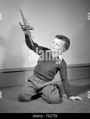 1940s BOY PLAYING WITH TOY MODEL OF FOUR ENGINE PROPELLOR AIRPLANE - j10075 HAR001 HARS OLD FASHIONED Stock Photo