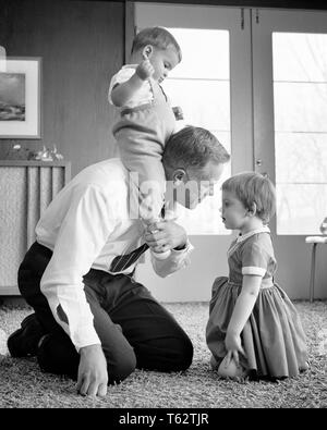 1960s FATHER PLAYING ON FLOOR WITH CHILDREN KNEELING WITH TODDLER GIRL BABY BOY SITTING ON HIS SHOULDERS - j11792 HAR001 HARS SISTER 1 JUVENILE SONS PARENTING FEMALES BROTHERS HOME LIFE COPY SPACE FRIENDSHIP HALF-LENGTH DAUGHTERS PERSONS CARING MALES SIBLINGS SISTERS FATHERS B&W KNEELING HAPPINESS HIS DADS SIBLING BABY BOY PIGGY BACK GROWTH JUVENILES PIGGYBACK TOGETHERNESS BLACK AND WHITE CAUCASIAN ETHNICITY HAR001 OLD FASHIONED Stock Photo