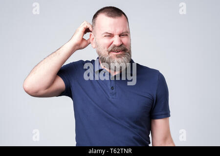 man looking aside scratching head. I have no idea how it happened. Stock Photo
