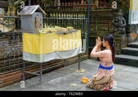 Young woman giving thanks in prayer, Pura Tirta Empul, Ubud, Bali, Indonesia Stock Photo