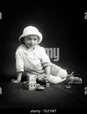 1900s PORTRAIT BOY WEARING NAUTICAL SAILOR OUTFIT SITTING POSING WITH TOYS ALPHABET BLOCKS TOPS STUFFED ANIMAL RABBIT - o3768 HAR001 HARS EYE CONTACT ALPHABET HAPPINESS TOPS POSING STYLISH GROWTH JUVENILES BLACK AND WHITE CAUCASIAN ETHNICITY HAR001 OLD FASHIONED Stock Photo