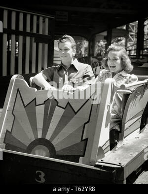 1930s 1940s TEENAGE COUPLE LAUGHING SMILING ANTICIPATING TAKING RIDE ON ROLLER COASTER IN AMUSEMENT PARK - p2136 HAR001 HARS STRESS NOSTALGIC PAIR ROMANCE SUBURBAN EXPRESSION OLD TIME BUSY NOSTALGIA OLD FASHION 1 JUVENILE FACIAL FEAR YOUNG ADULT SAFETY RIDE PLEASED JOY LIFESTYLE SPEED CELEBRATION FEMALES RURAL COPY SPACE FRIENDSHIP LADIES PERSONS MALES RISK TEENAGE GIRL FRIGHTENED TEENAGE BOY ENTERTAINMENT CONFIDENCE EXPRESSIONS B&W AMUSEMENT HAPPINESS HEAD AND SHOULDERS CHEERFUL ADVENTURE LEISURE CHOICE EXCITEMENT RECREATION IN ON SMILES ANTICIPATING CONCEPTUAL JOYFUL STYLISH TEENAGED FRIGHT Stock Photo
