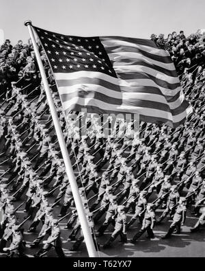 1940s NEW YORK CITY PATTERN OF MARCHING MEN TROOPS WITH USA 48 STAR FLAG SUPERIMPOSED IN FOREGROUND - q42140 CPC001 HARS SPIRITUALITY B&W FREEDOM SUCCESS HIGH ANGLE STRENGTH VICTORY COURAGE EXCITEMENT LEADERSHIP POWERFUL GOTHAM WORLD WARS DIRECTION PRIDE WORLD WAR WORLD WAR TWO WORLD WAR II IN OF AUTHORITY NYC OCCUPATIONS POLITICS TROOPS UNIFORMS CONCEPTUAL NEW YORK CITIES STYLISH WORLD WAR 2 48 STAR NEW YORK CITY HONOR PRECISION RED WHITE AND BLUE STARS AND STRIPS BLACK AND WHITE DUTY FOREGROUND OLD FASHIONED SUPERIMPOSED Stock Photo