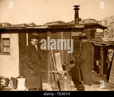 1930s TWO MEN IN HATS AND OVERCOATS STANDING BY HOOVERVILLE SHANTY TOWN TRAILER PARK DEPRESSION VILLAGE VARIOUS CITIES USA - q73981 CPC001 HARS COPY SPACE FULL-LENGTH PERSONS VILLAGE UNITED STATES OF AMERICA MALES RISK ROUGH EXPRESSIONS B&W SADNESS SHELTER DISASTER HOMELESS STRENGTH STRATEGY AND EXTERIOR POWERFUL PROGRESS CONDITIONS BY IN POLITICS OVERCOATS CONCEPTUAL CITIES TEMPORARY VARIOUS ANONYMOUS BUILT COOPERATION MID-ADULT MID-ADULT MAN SHANTY TOGETHERNESS BLACK AND WHITE CAUCASIAN ETHNICITY DEFEATED DURING GREAT DEPRESSION HOOVERVILLE OLD FASHIONED SHANTY TOWN Stock Photo