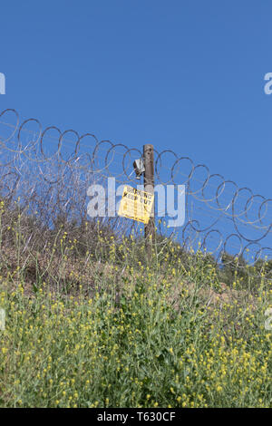 Warning keep out sign and barbed wire fence  attached to a wooden post marking a private property boundary in a rural area Stock Photo