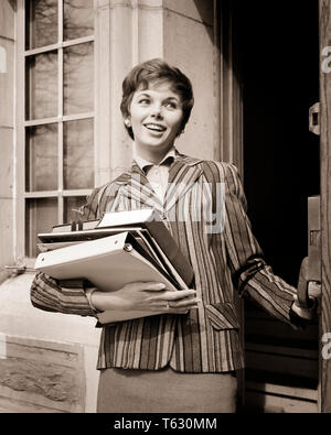 1950s 1960s SMILING COED WALKING OUT OF DOOR CARRYING BOOKS NOTEBOOKS WEARING STRIPED JACKET - s8304 HAR001 HARS COPY SPACE HALF-LENGTH LADIES PERSONS CONFIDENCE B&W BRUNETTE HAPPINESS CHEERFUL STYLES NOTEBOOKS PRIDE SMILES JOYFUL STYLISH COED FASHIONS YOUNG ADULT WOMAN BLACK AND WHITE CAUCASIAN ETHNICITY HAR001 OLD FASHIONED Stock Photo