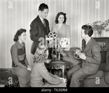 1940s GROUP OF SMILING YOUNG MEN AND WOMEN WITH REELS OF FILM SETTING UP HOME MOVIE PROJECTOR - u591 HAR001 HARS OLD FASHION JUVENILE STYLE COMMUNICATION YOUNG ADULT RELAXING LIFESTYLE FIVE FEMALES 5 HOME LIFE FRIENDSHIP FULL-LENGTH HALF-LENGTH LADIES PERSONS MALES TEENAGE GIRL TEENAGE BOY ENTERTAINMENT B&W SKILL ACTIVITY AMUSEMENT PROJECTOR HOBBY LEISURE INTEREST AND HOBBIES KNOWLEDGE RECREATION PASTIME PLEASURE OF UP CONCEPTUAL STYLISH TEENAGED JUVENILES REELS RELAXATION TOGETHERNESS YOUNG ADULT MAN YOUNG ADULT WOMAN AMATEUR BLACK AND WHITE CAUCASIAN ETHNICITY ENJOYMENT HAR001 OLD FASHIONED Stock Photo