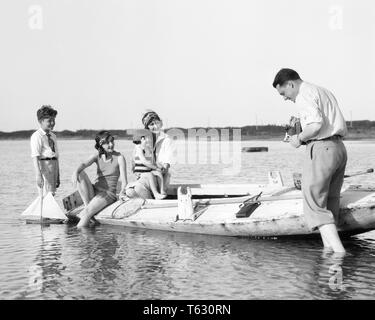 1920s FATHER WITH FOLDING KODAK CAMERA PHOTOGRAPHING WIFE SON DAUGHTER AND AUNT ON WOODEN DUCK BOAT BARNEGAT BAY NEW JERSEY USA - u840 HAR001 HARS MOM WOODEN NOSTALGIC PAIR BEAUTY MOTHERS OLD TIME NOSTALGIA BROTHER OLD FASHION SISTER 1 JUVENILE COMMUNICATION YOUNG ADULT TEAMWORK VACATION RELAXING SONS PLEASED FAMILIES JOY LIFESTYLE FIVE CELEBRATION FEMALES MARRIED 5 BROTHERS RURAL SPOUSE HUSBANDS COPY SPACE FULL-LENGTH LADIES DAUGHTERS PERSONS MALES FOLDING SIBLINGS SISTERS FATHERS B&W PARTNER TIME OFF SKILL ACTIVITY AMUSEMENT HAPPINESS CHEERFUL HOBBY TRIP INTEREST AND GETAWAY DADS EXCITEMENT Stock Photo