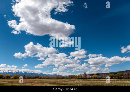 Beautiful clouds and sky over ranch pastures; snow capped Rocky Mountains beyond; central Colorado; USA